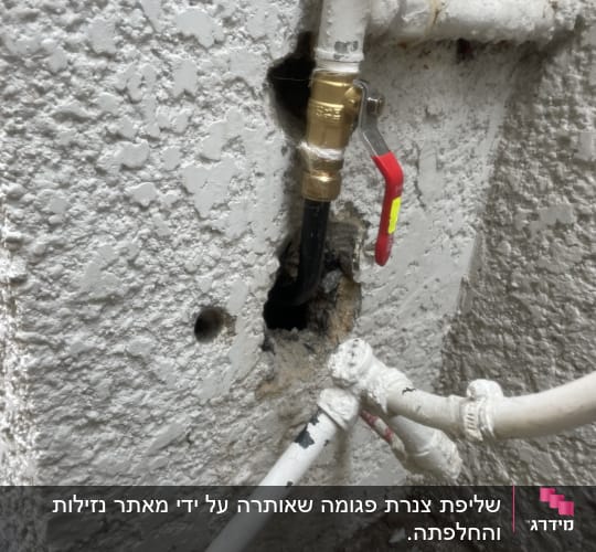 צינור עם ברז ומחברים בקיר בטון